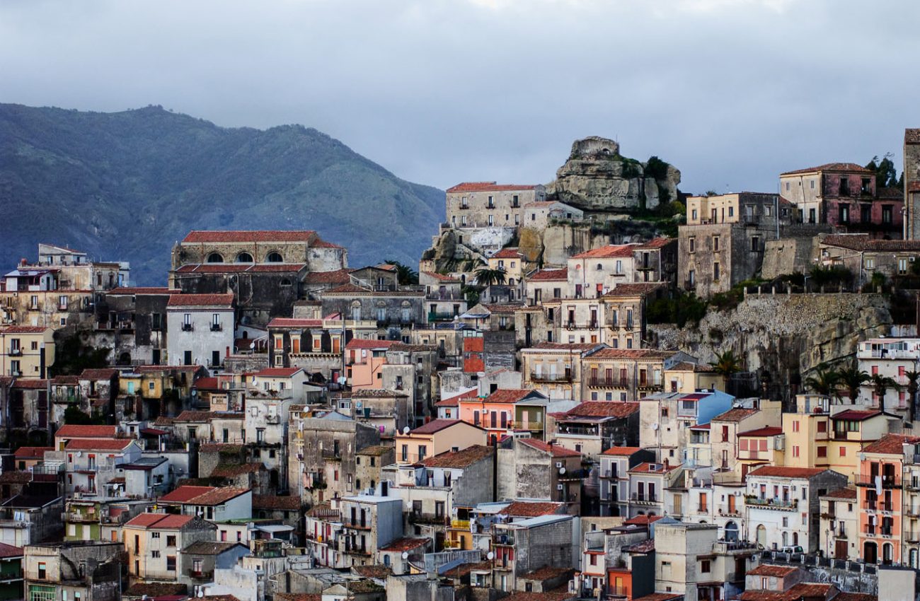 Colorful houses in Sicilian village with mountains in the background